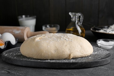 Photo of Fresh yeast dough with flour on black table