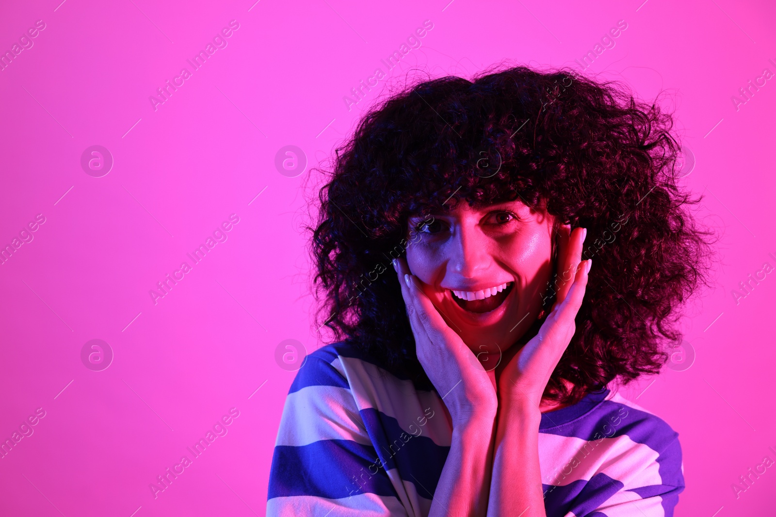 Photo of Beautiful young woman posing on color background in neon lights. Space for text