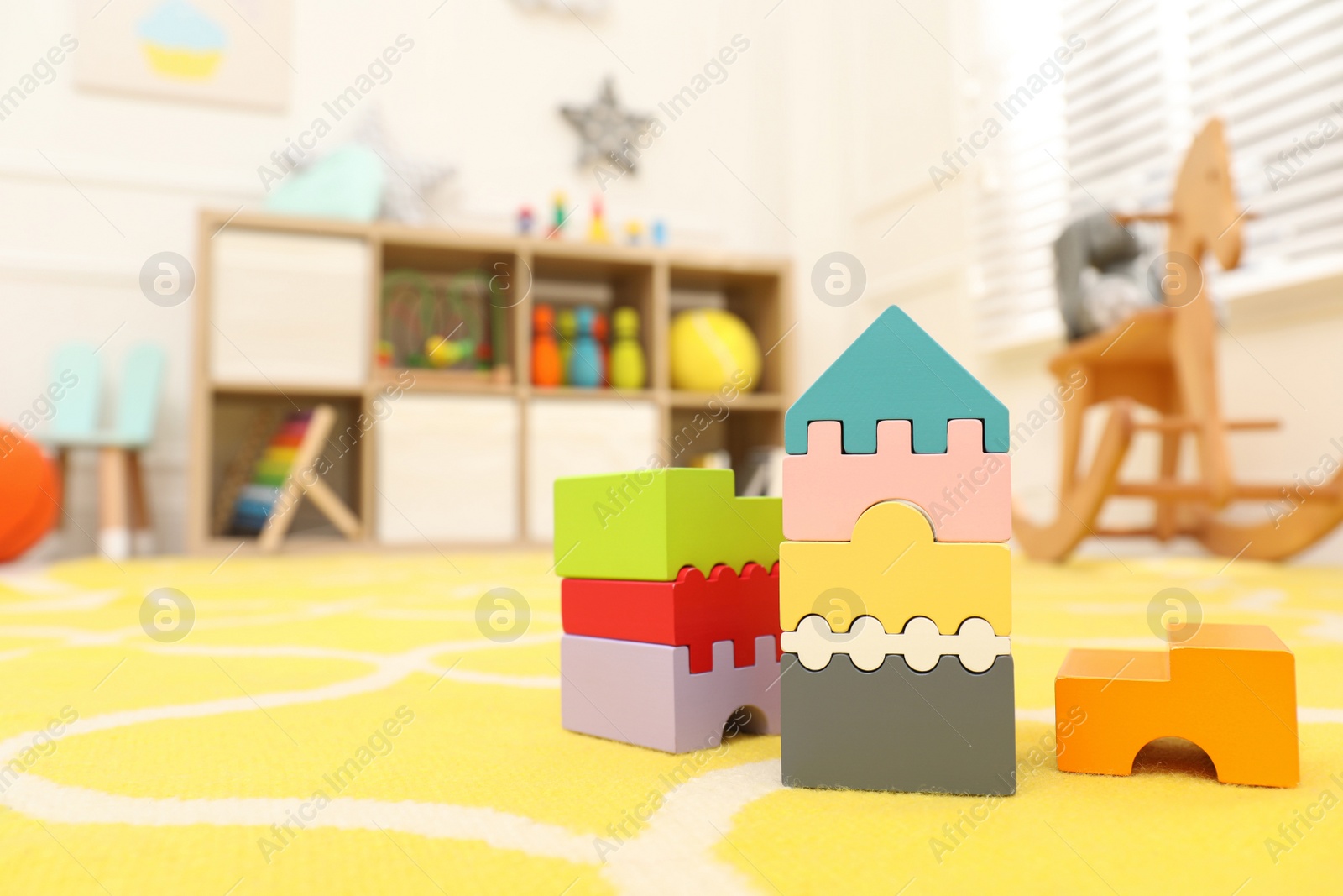 Photo of Wooden castle made of colorful blocks on carpet in playroom, space for text. Interior design