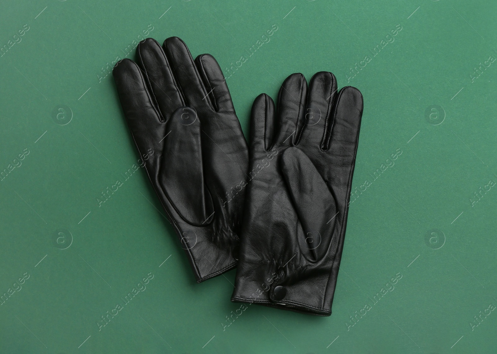 Photo of Pair of stylish leather gloves on green background, flat lay