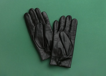 Pair of stylish leather gloves on green background, flat lay