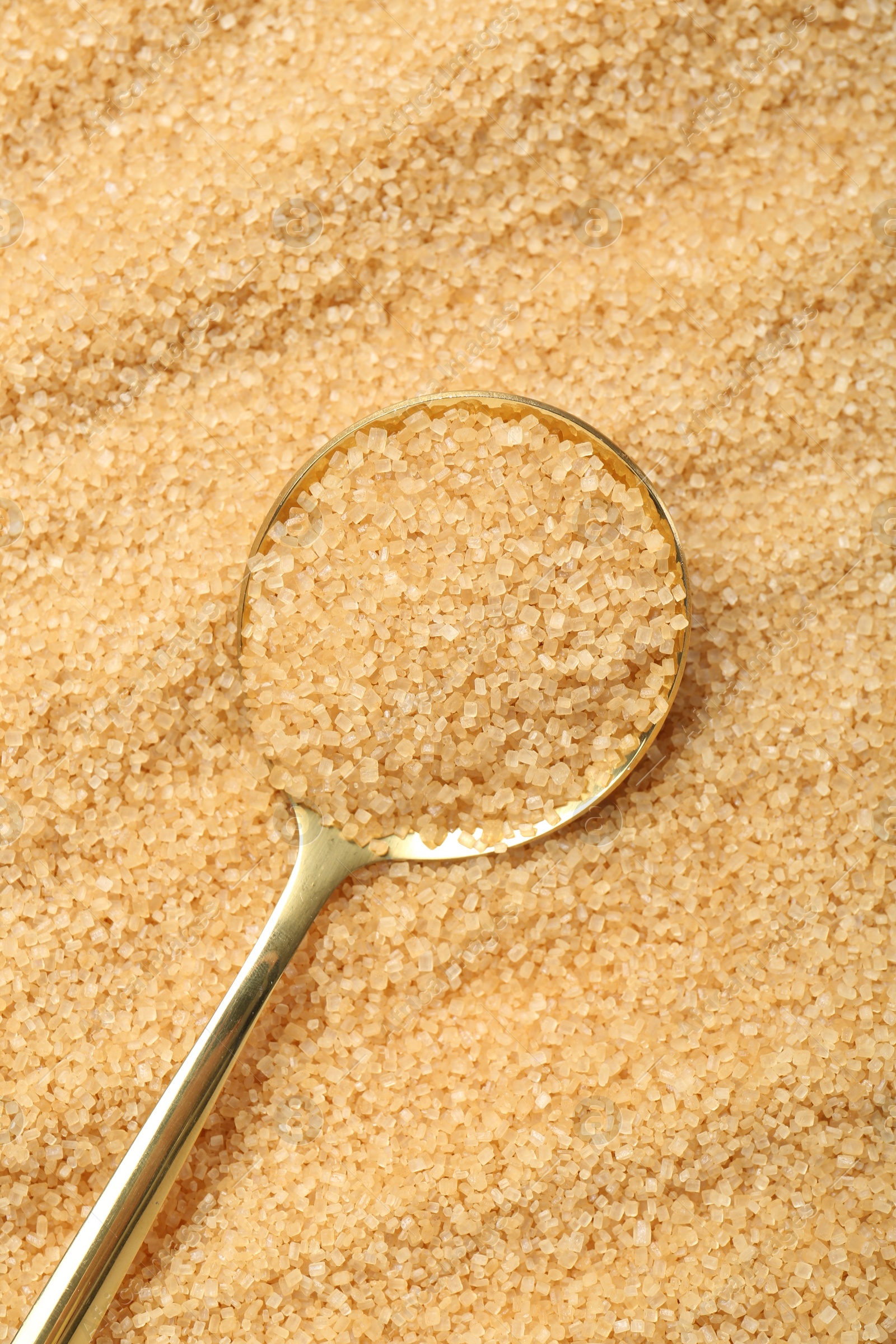 Photo of Spoon on granulated brown sugar, top view