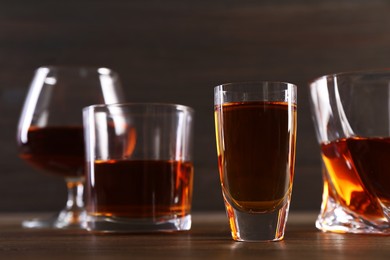 Different delicious liqueurs in glasses on wooden table