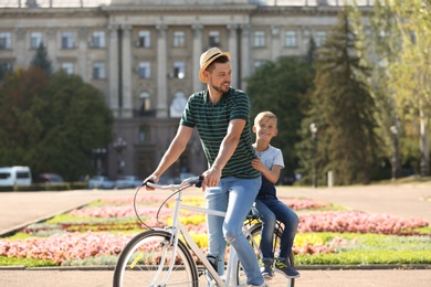 Photo of Father and son riding bicycle on street