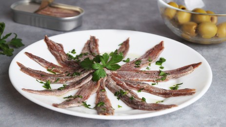 Photo of Plate with anchovy fillets and parsley on grey table