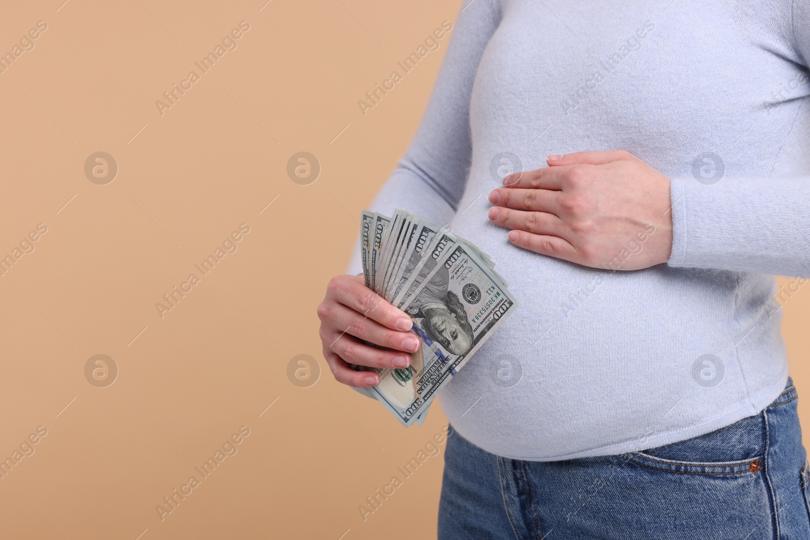 Photo of Surrogate mother. Pregnant woman with dollar banknotes on beige background, closeup. Space for text