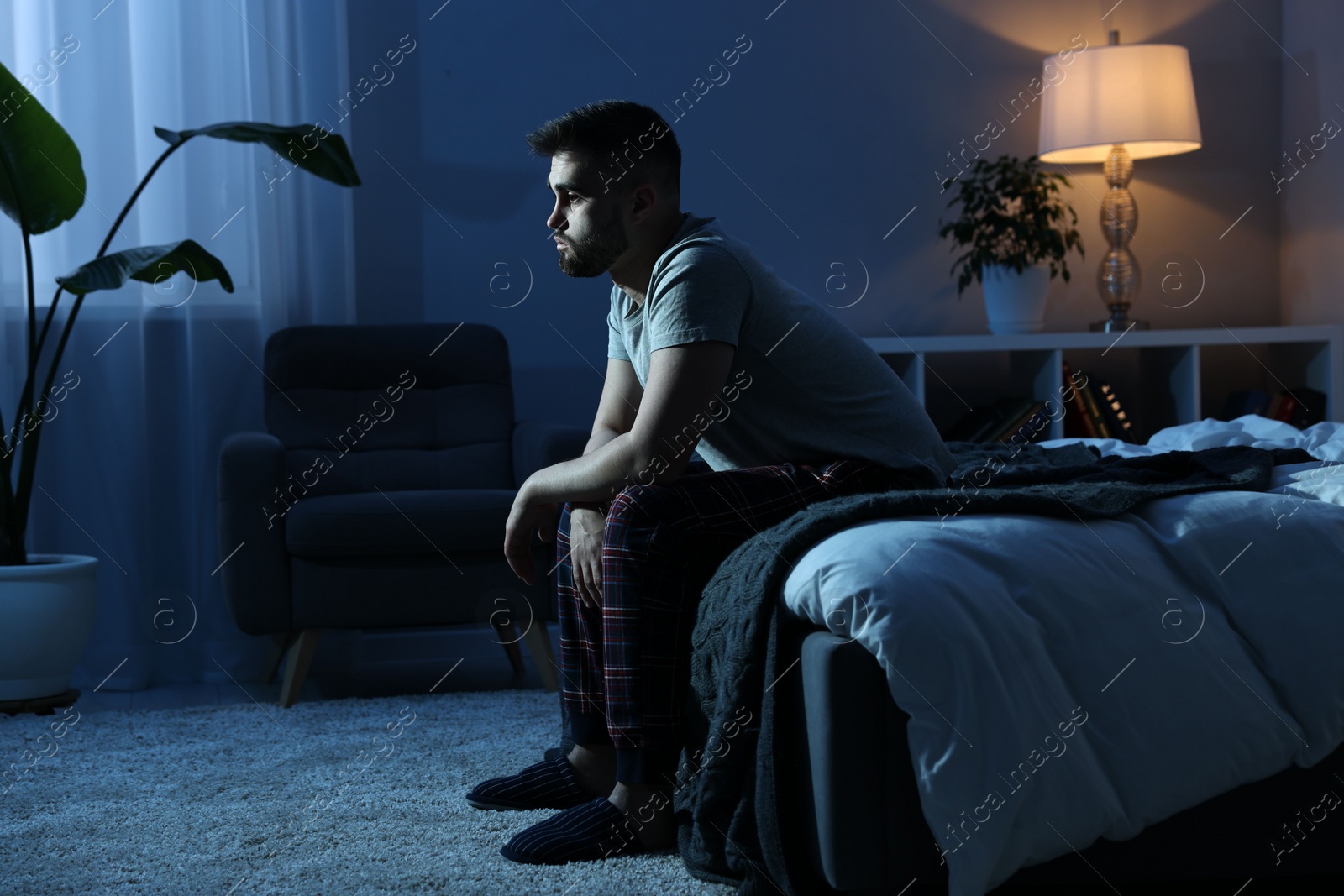 Photo of Frustrated man sitting on bed at night