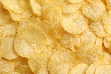 Crispy potato chips as background, top view