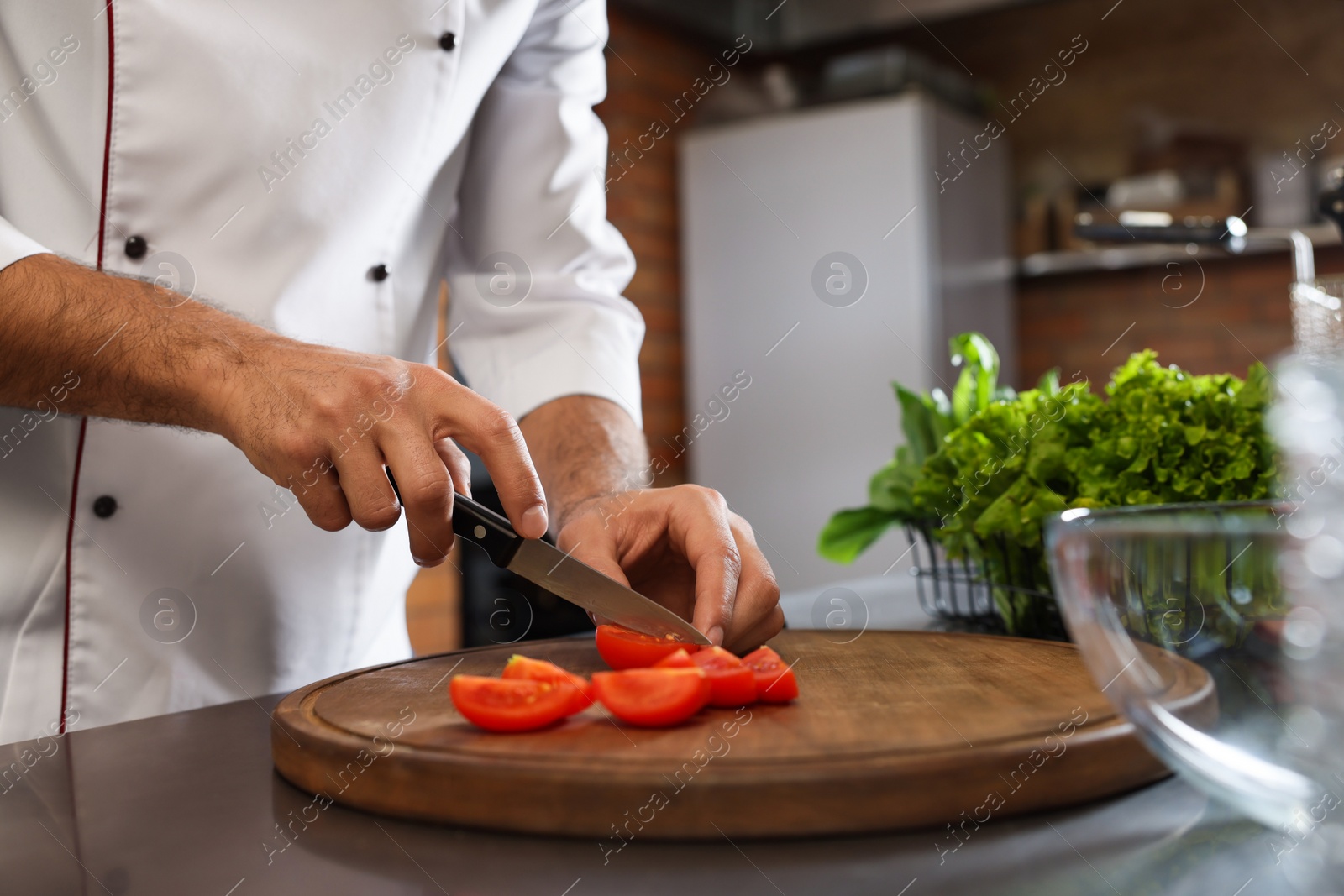 Photo of Professional chef cutting fresh tomatoes in restaurant kitchen, closeup