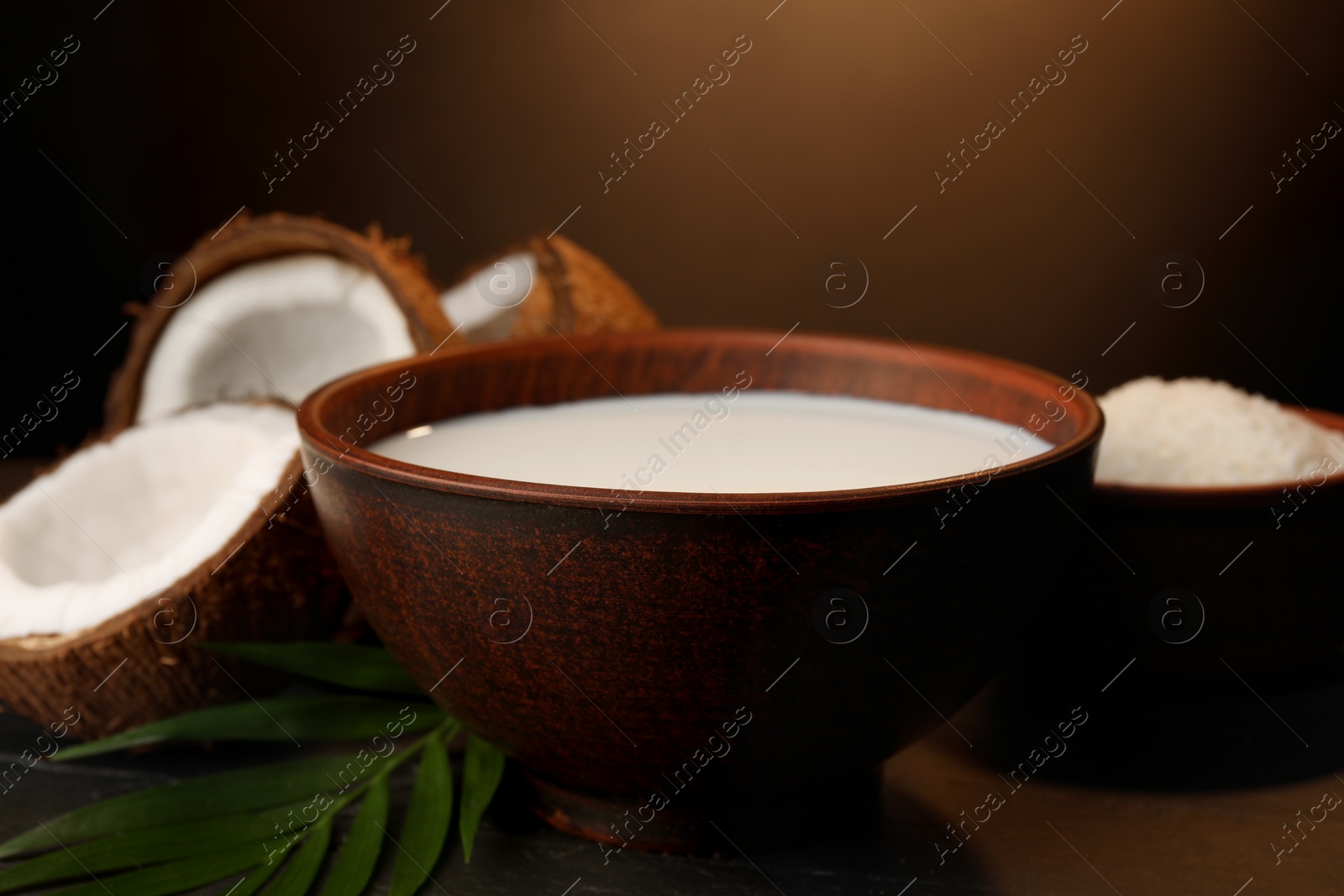 Photo of Bowl of delicious vegan milk near coconut pieces on table, closeup