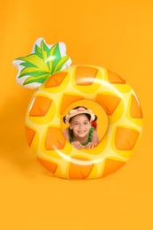 Photo of Cute little child with bright inflatable ring on yellow background. Beach holiday