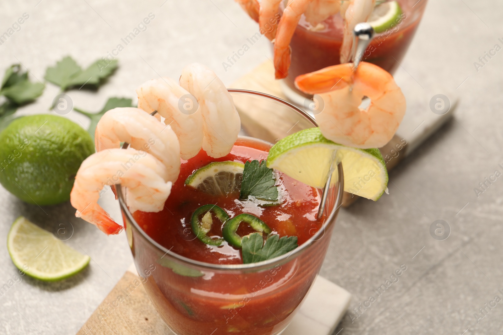 Photo of Tasty shrimp cocktail with sauce in glasses and lime on light table, closeup