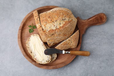 Tasty bread with butter and knife on grey textured table, top view