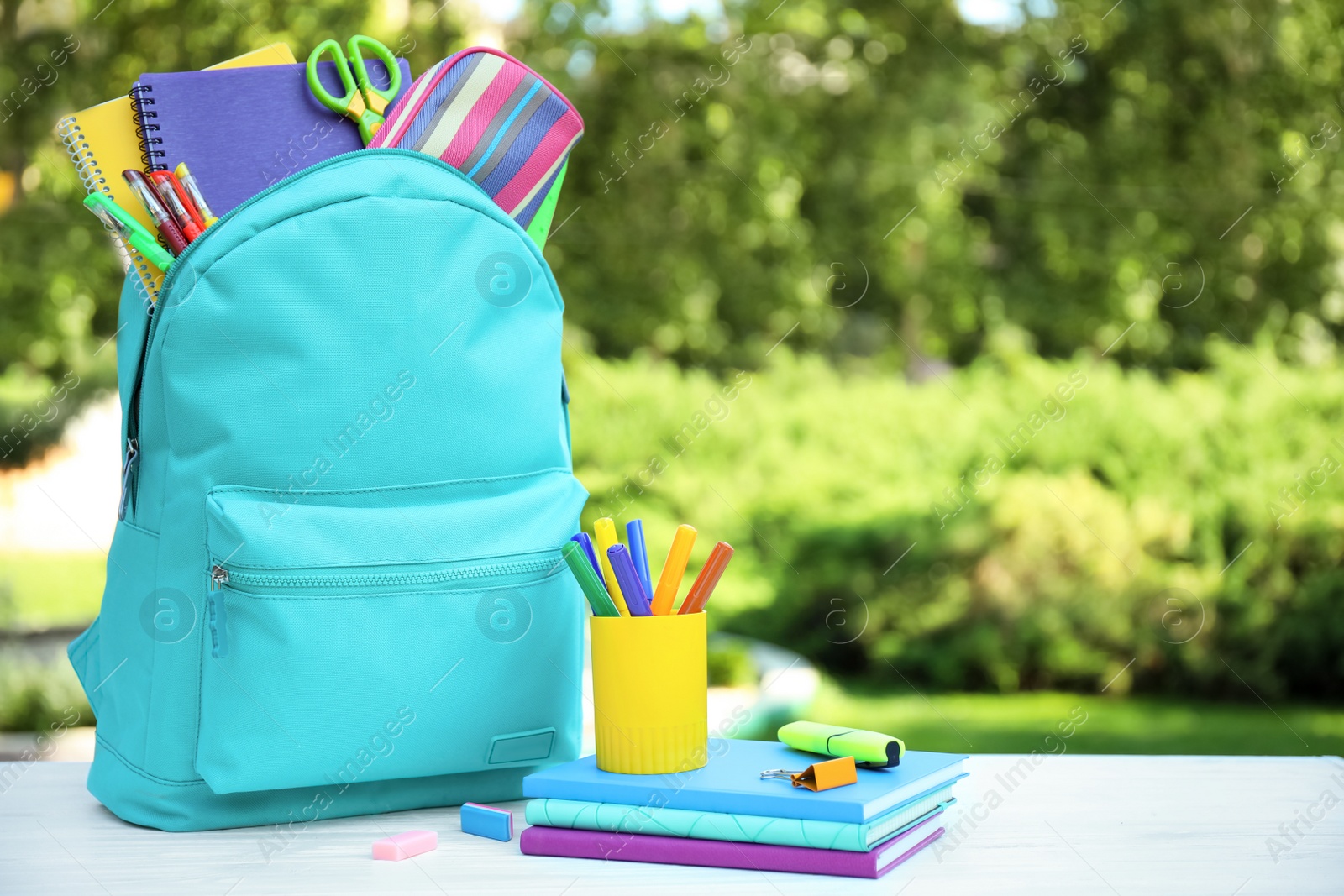 Photo of Bright backpack and school stationery on table outdoors, space for text