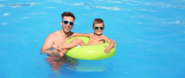 Image of Little boy on inflatable ring with happy father in swimming pool. Banner design
