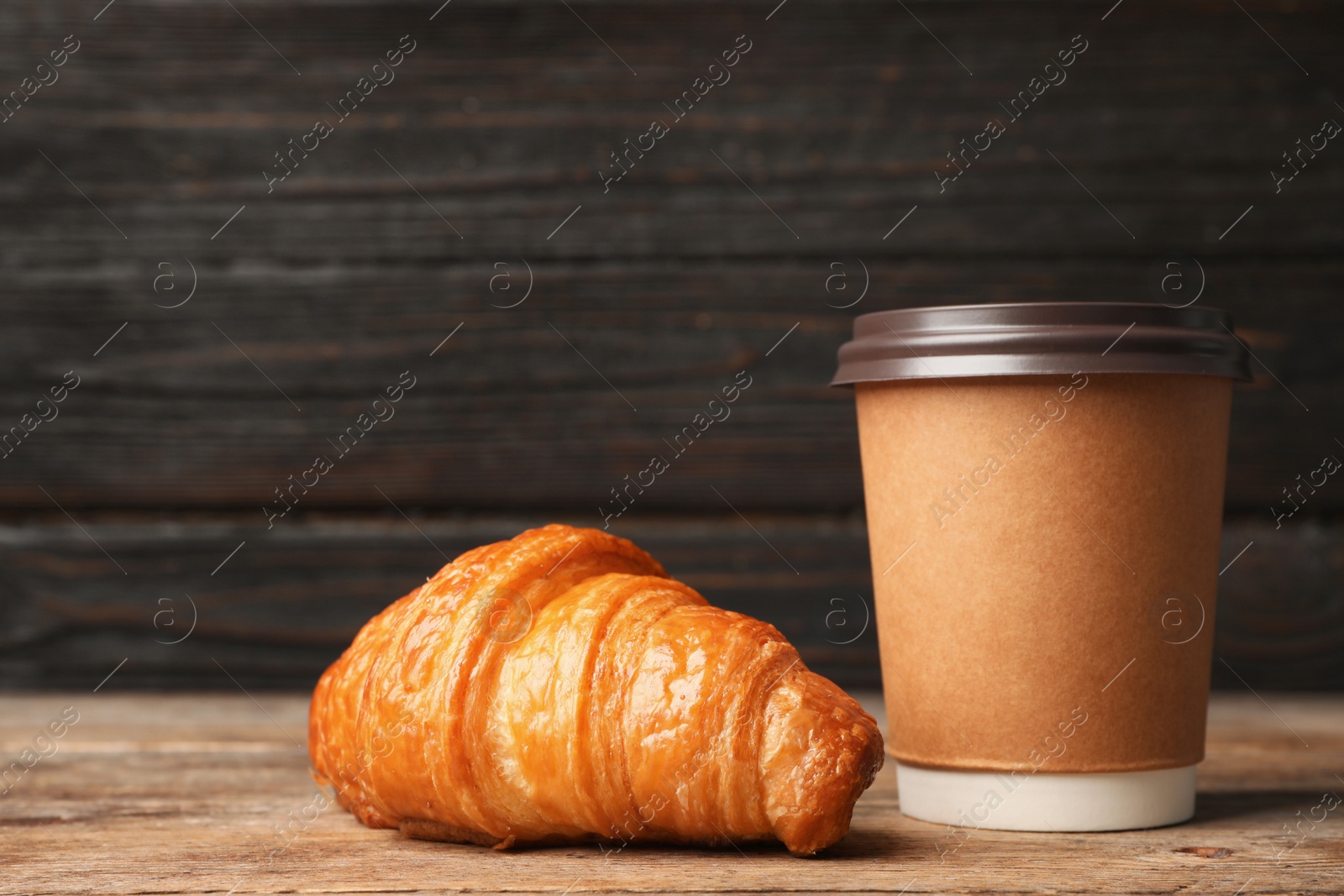 Photo of Paper cup with aromatic coffee and croissant on wooden table. Mockup for design