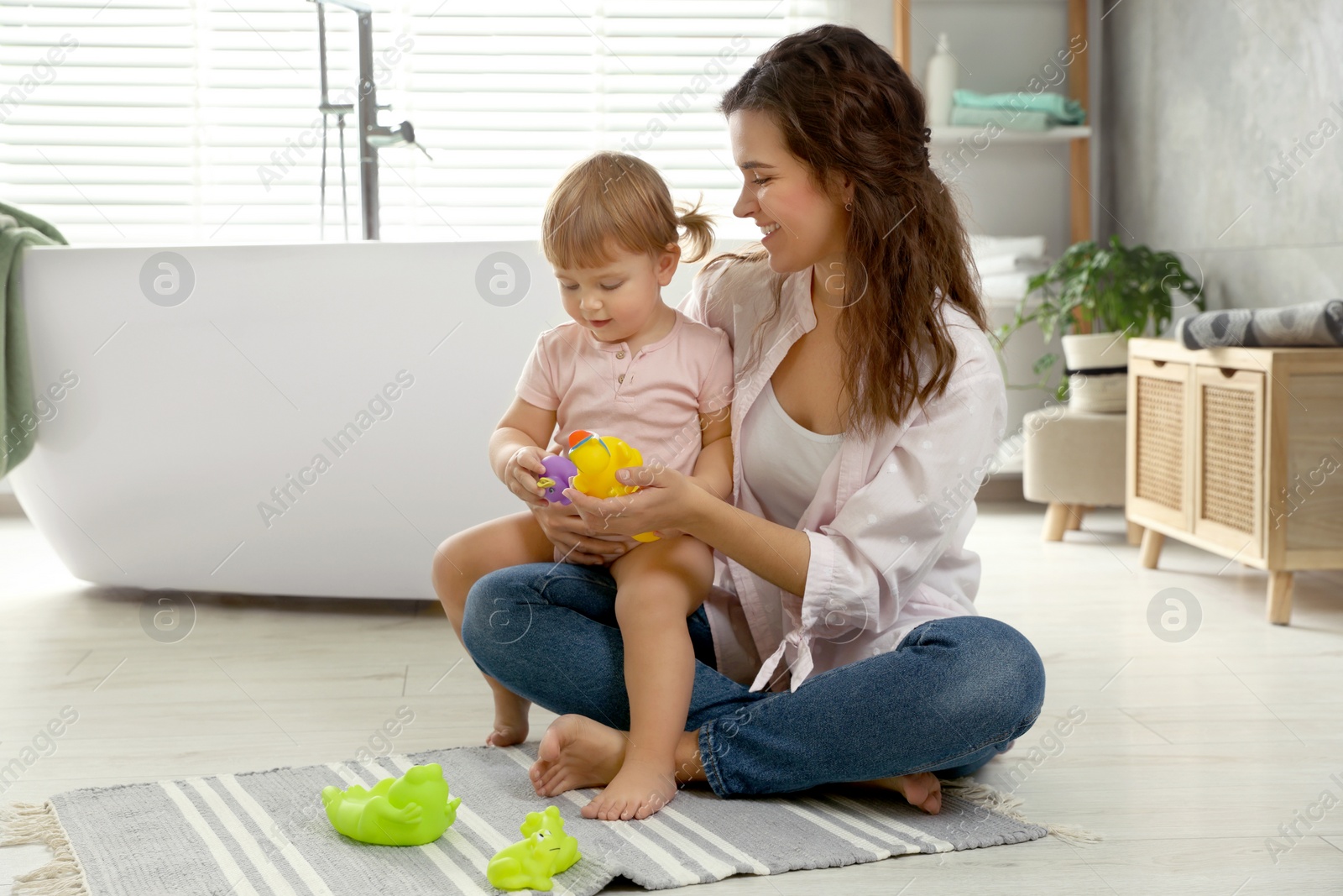 Photo of Mother playing with her daughter in bathroom