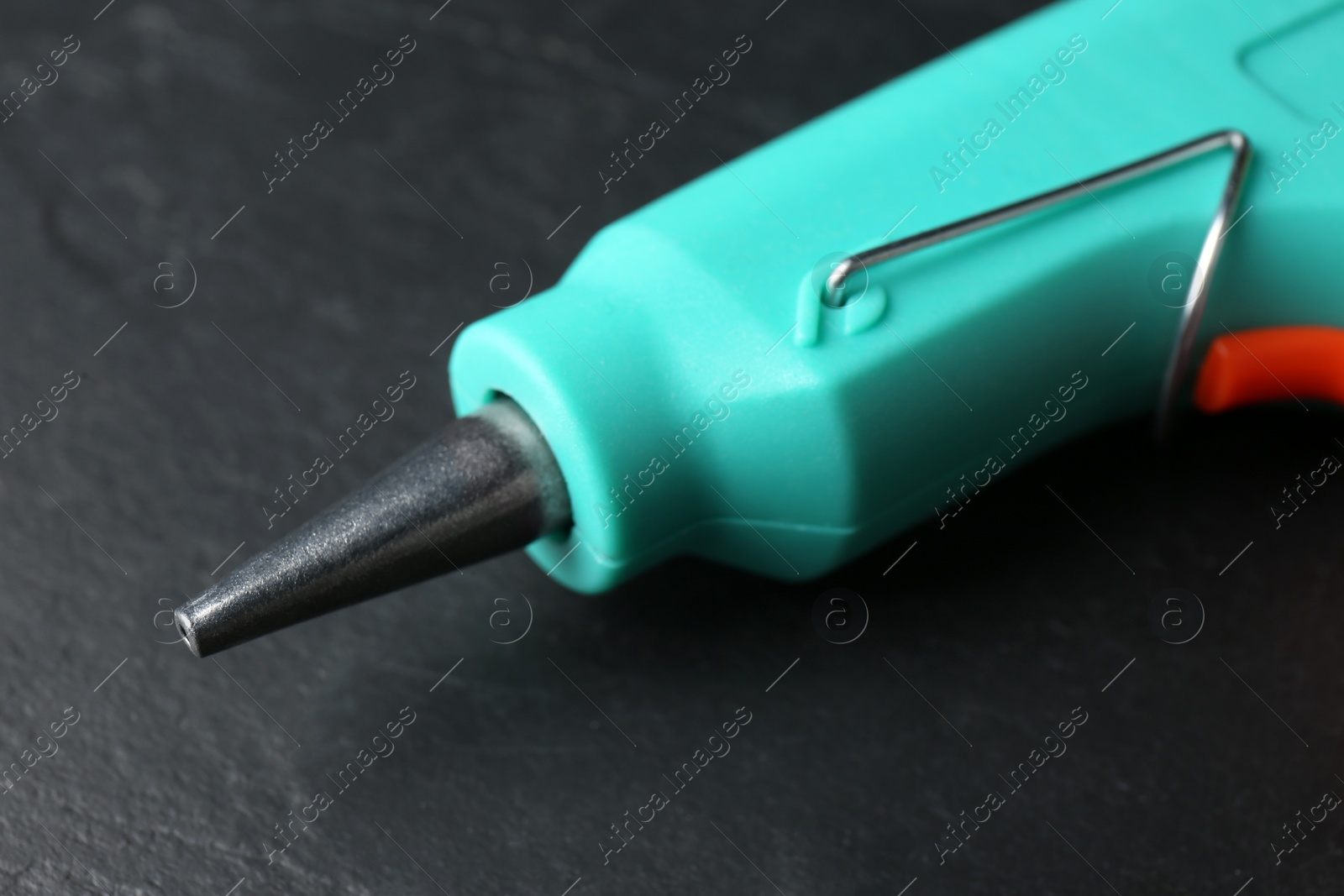 Photo of Hot glue gun on dark grey table, closeup