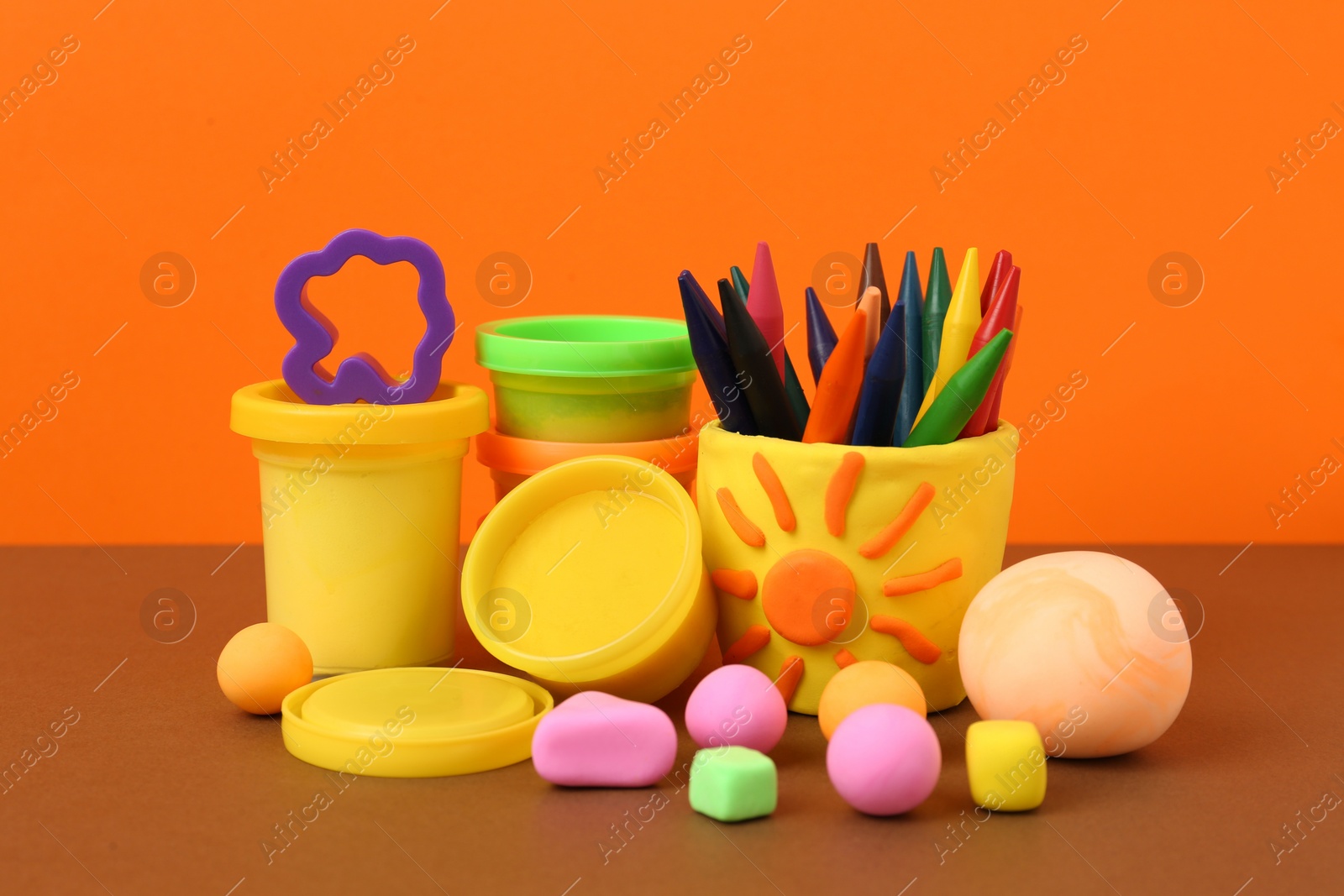 Photo of Set of bright play dough with mold and pencils on color background