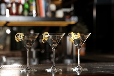 Photo of Glasses of lemon drop martini cocktail on bar counter. Space for text