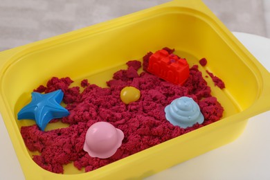 Photo of Bright kinetic sand and toys in yellow basin