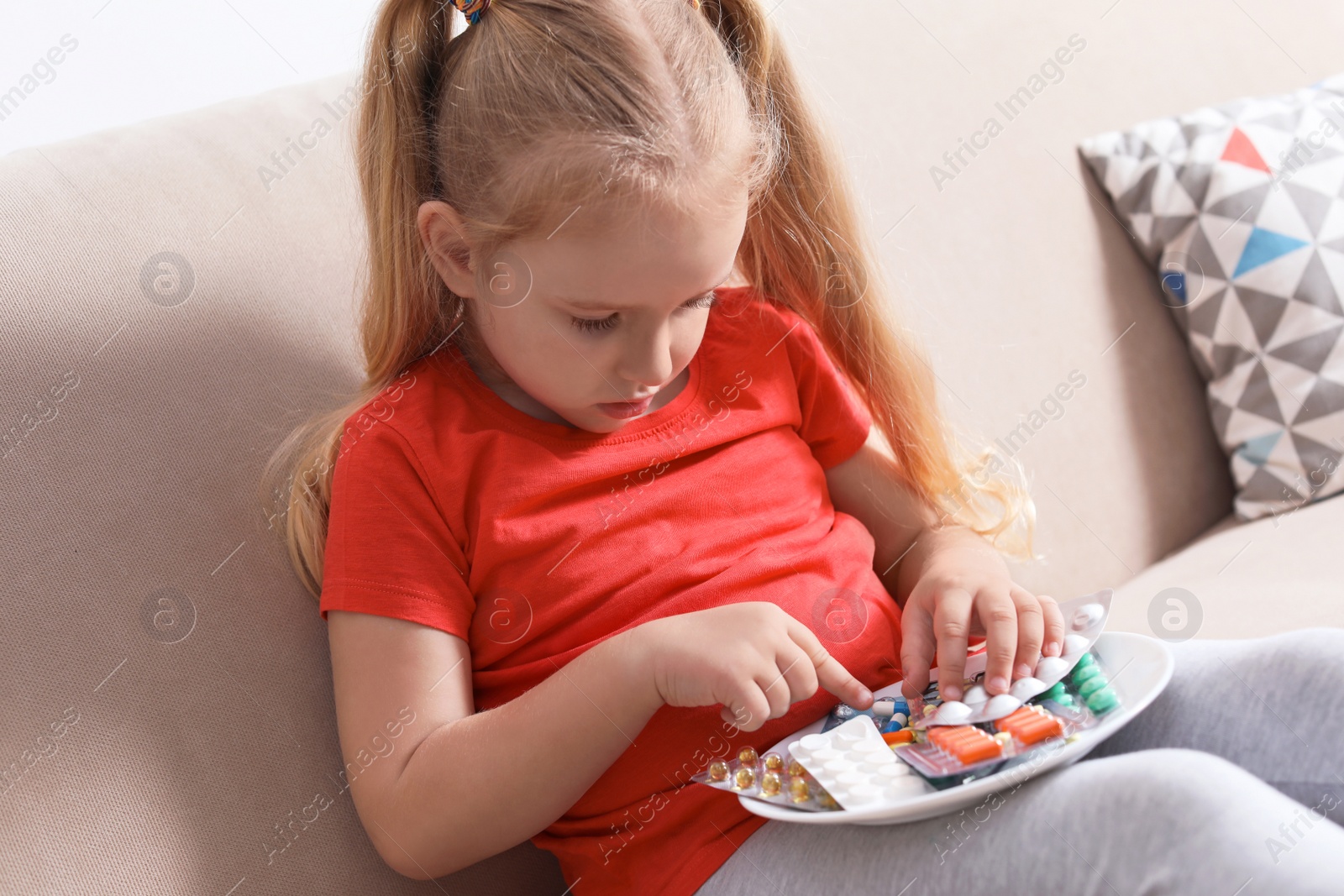 Photo of Little child with plate of different pills at home. Household danger