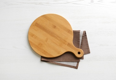 Photo of Empty wooden board and napkin on white table, top view