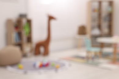 Stylish kindergarten interior with toys and modern furniture, blurred view