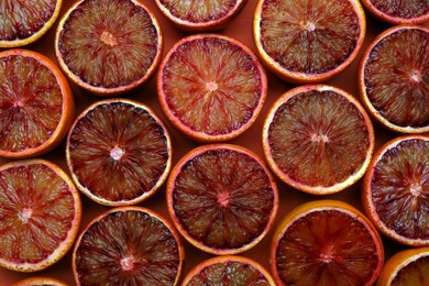 Photo of Slices of ripe sicilian oranges on red background, flat lay