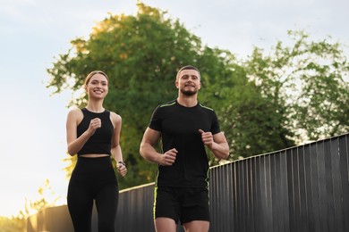 Photo of Attractive sporty couple in fitness clothes jogging outdoors