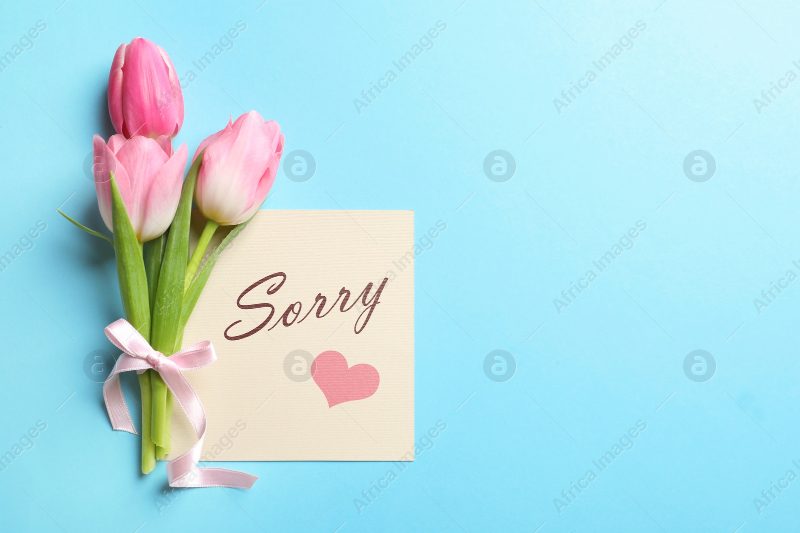 Image of Card with word Sorry and bouquet of tulips on light blue background, flat lay. Space for text
