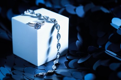 Photo of Elegant jewelry. Stylish presentation of luxury bracelet and ring on podium. Space for text