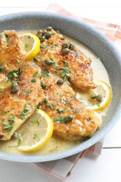 Delicious chicken piccata on white wooden table, closeup