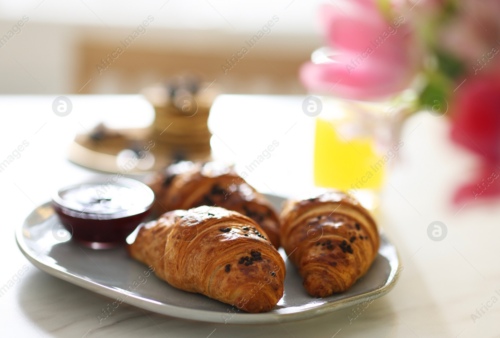 Photo of Tasty breakfast. Plate with fresh croissants on white marble table, closeup
