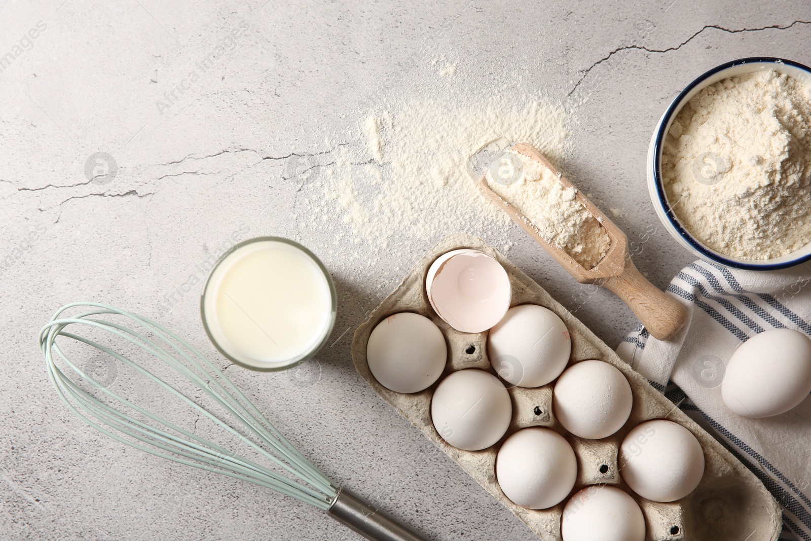 Photo of Making dough. Flour, eggs, milk and tools on light textured table, flat lay