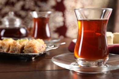 Photo of Traditional Turkish tea in glass on wooden table, closeup. Space for text