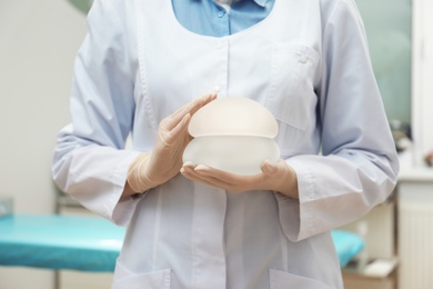 Doctor holding silicone implants for breast augmentation in clinic, closeup. Cosmetic surgery