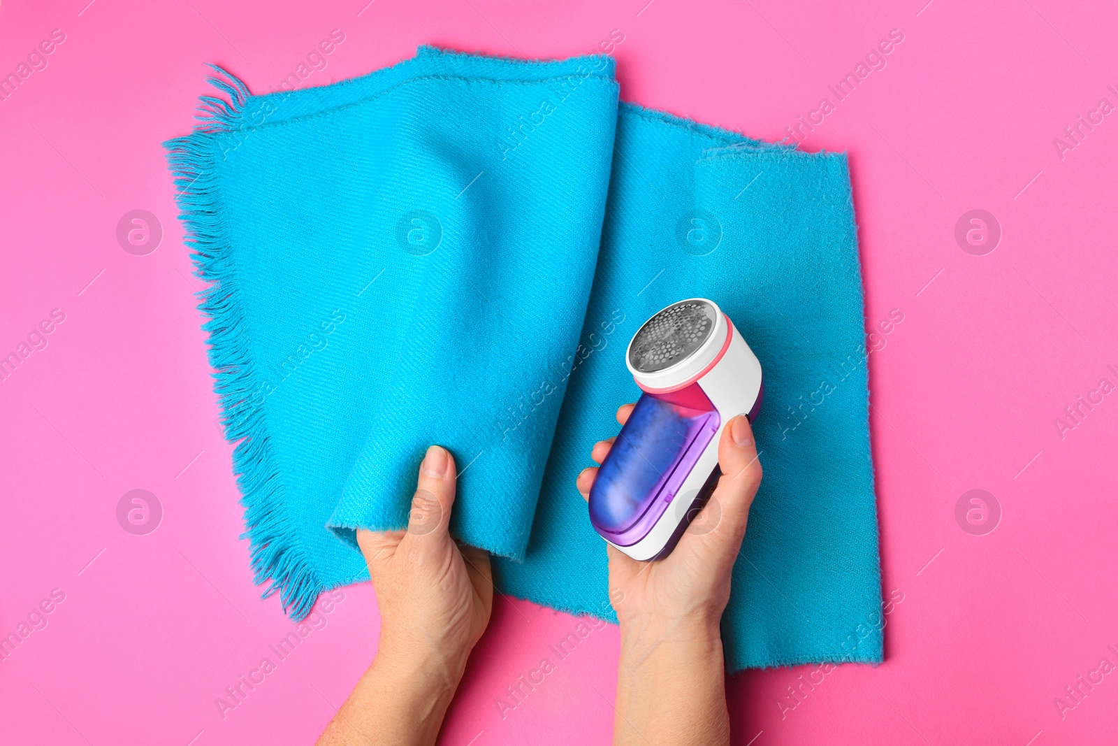 Photo of Woman with light blue scarf and fabric shaver on pink background, top view