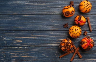 Flat lay composition with pomander balls made of fresh tangerines and cloves on blue wooden table, space for text