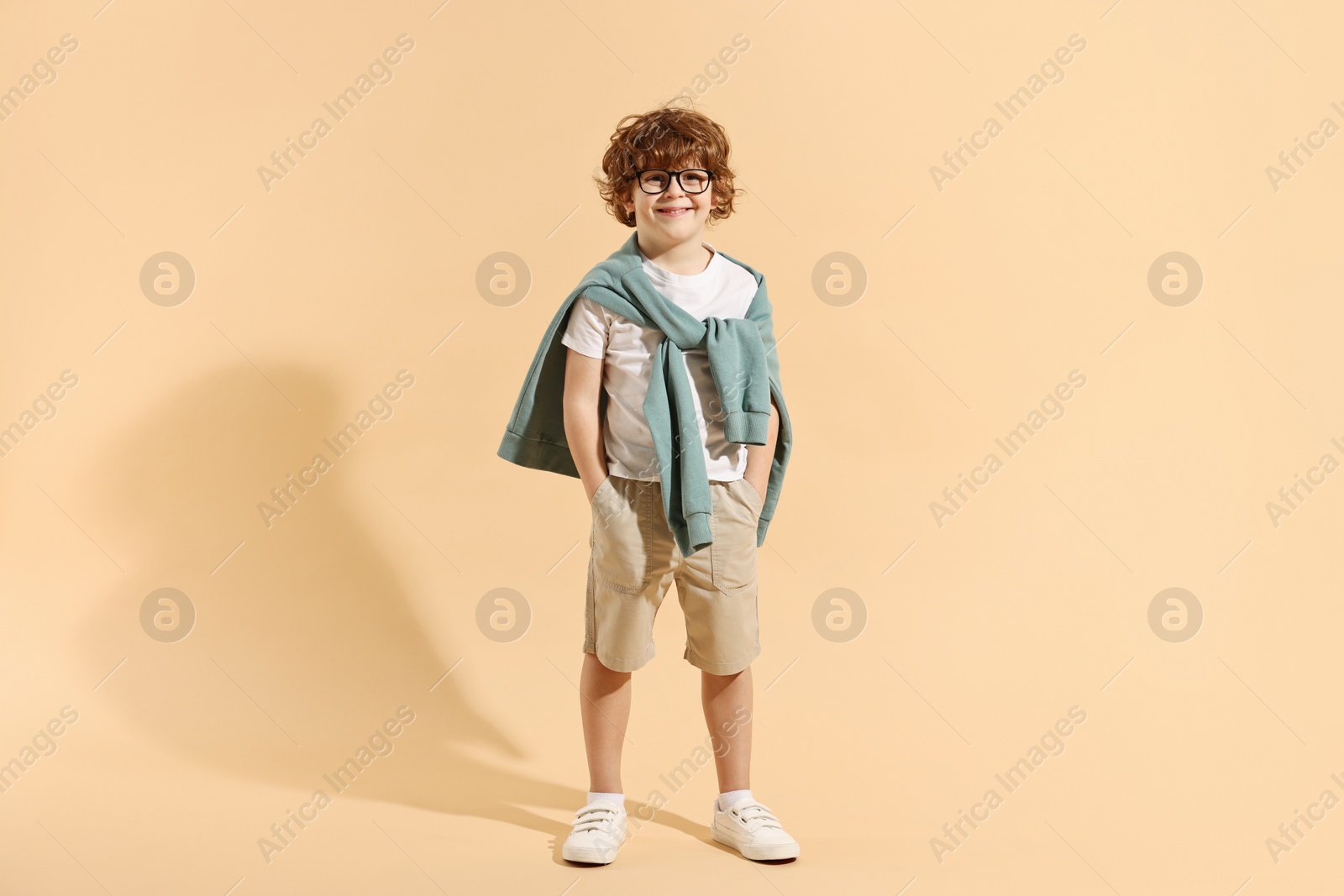 Photo of Fashion concept. Stylish boy on pale orange background