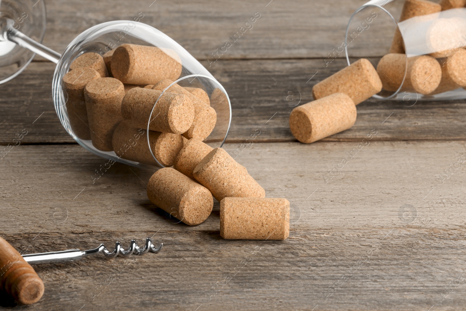 Photo of Glasses with wine corks and corkscrew on wooden table