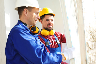 Workers in uniform dismantling old window indoors