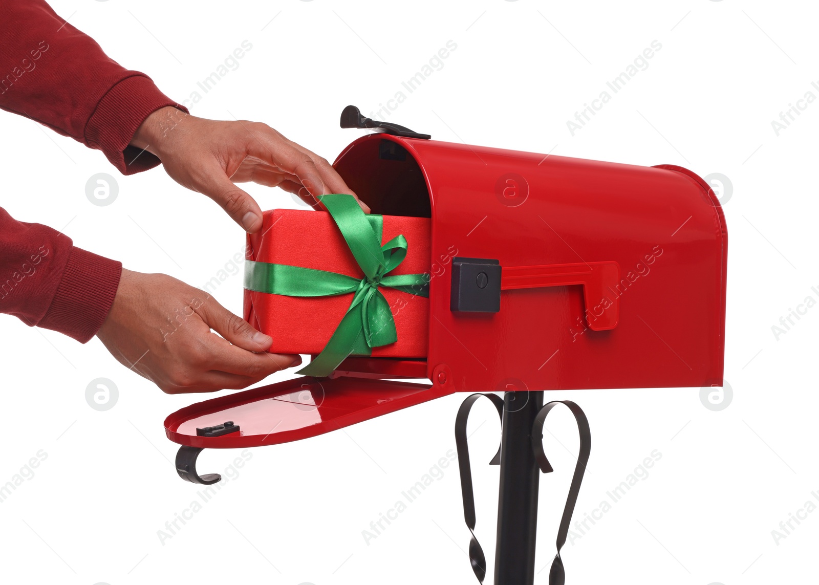 Photo of Man putting Christmas gift into mailbox on white background, closeup. Sending present by mail