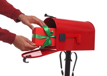 Man putting Christmas gift into mailbox on white background, closeup. Sending present by mail