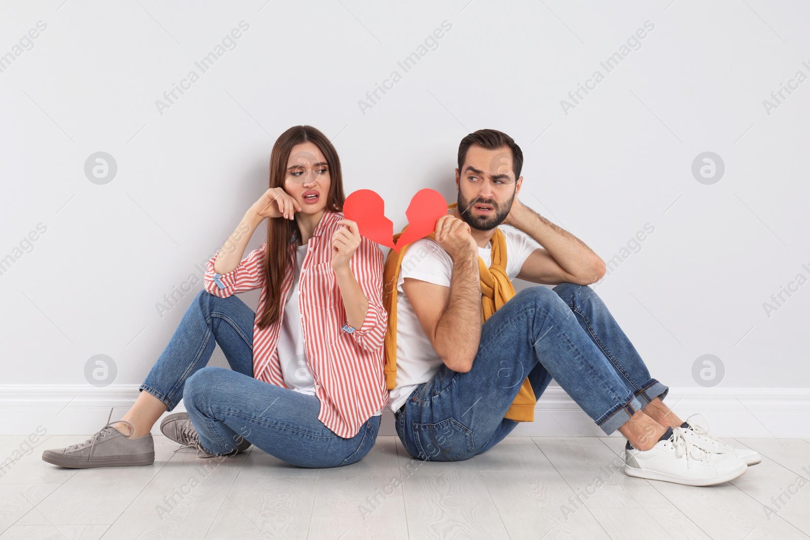 Photo of Couple with torn paper heart indoors. Relationship problems