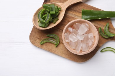 Photo of Aloe vera gel and slices of plant on white wooden table, top view. Space for text