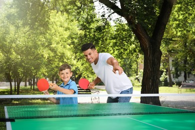 Photo of Man with his son playing ping pong in park