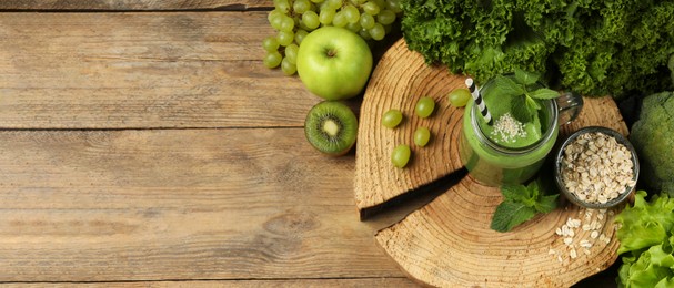 Mason jar of fresh green smoothie and ingredients on wooden table, flat lay. Space for text. Banner design