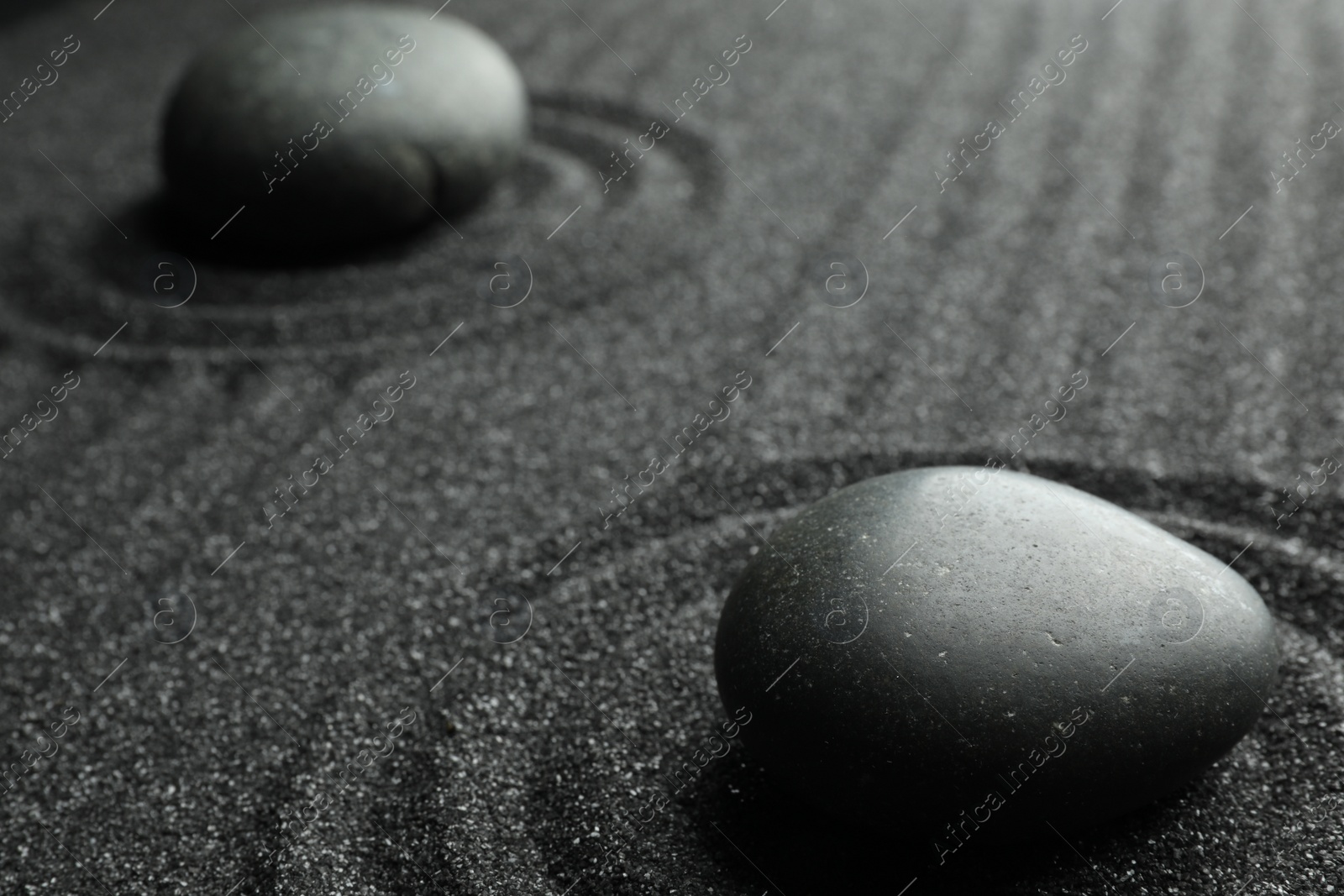 Photo of Black sand with stones and beautiful pattern. Zen concept