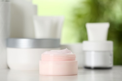 Photo of Jar of body care product on table against blurred background. Space for text